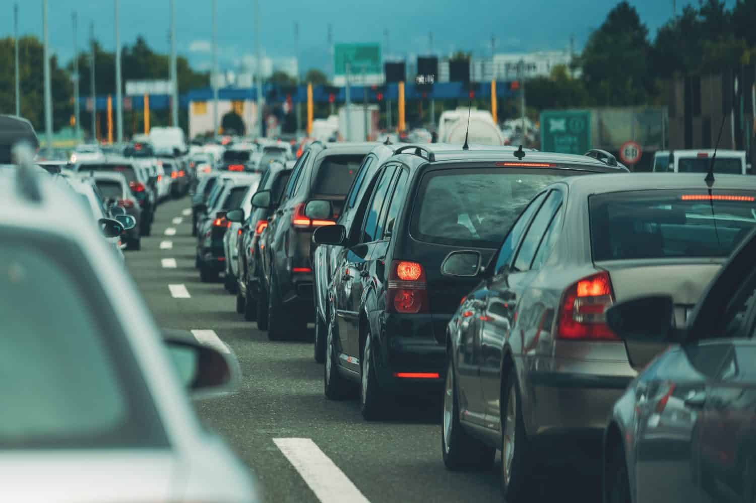 Large queue of vehicles on motorway pay toll in summer, selective focus