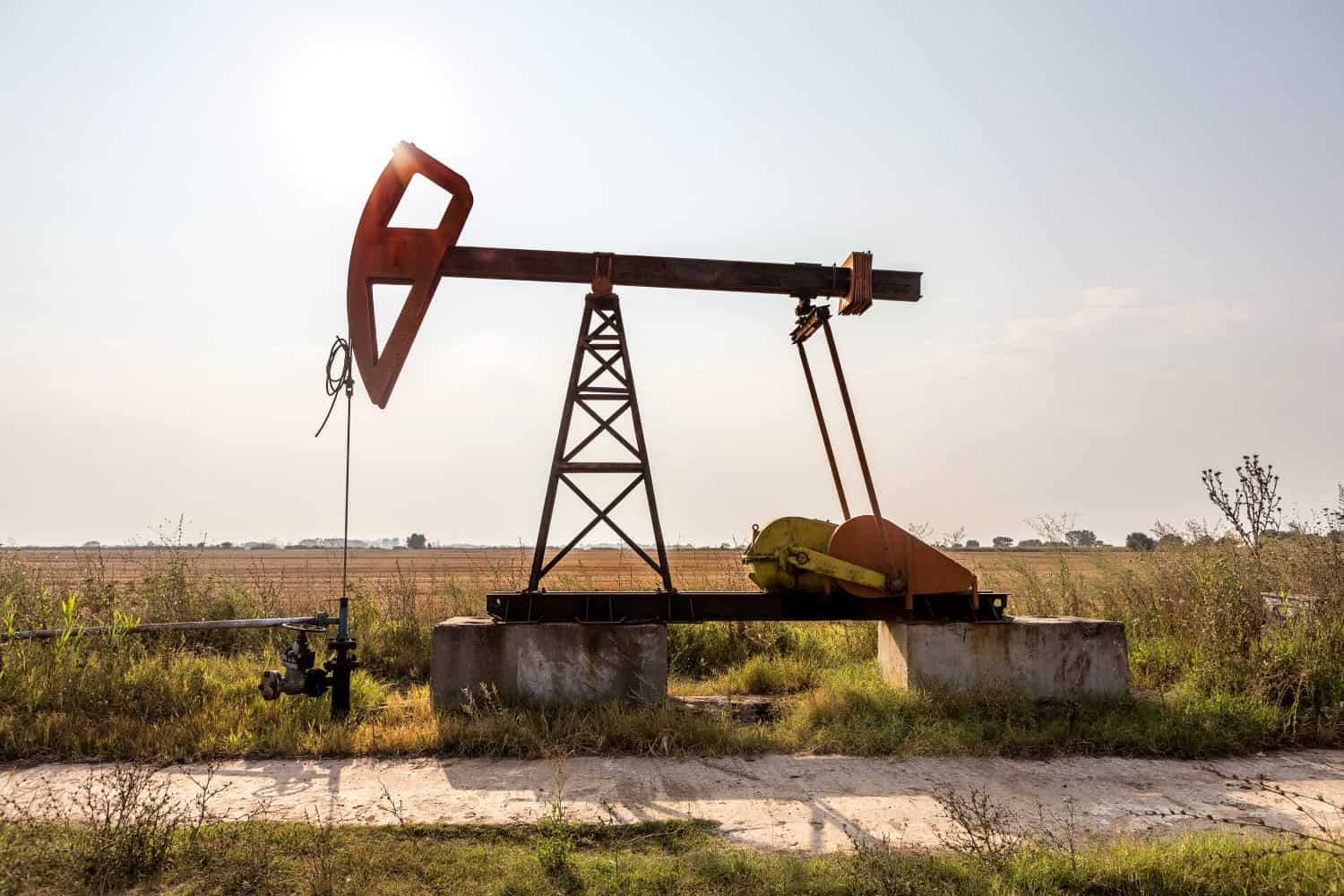A small private oil derrick pumps oil on the field. The old handicraft oil rig in the background of the creative industrial design. Illegal development of minerals. Bulgaria Tyulenovo, 2016