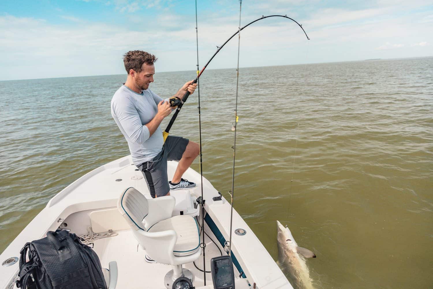 Fishing man sport fishing spinner shark on catch release fish activity boat tour pulling line. Fisherman outdoor in Everglades, Florida. Summer leisure recreation.