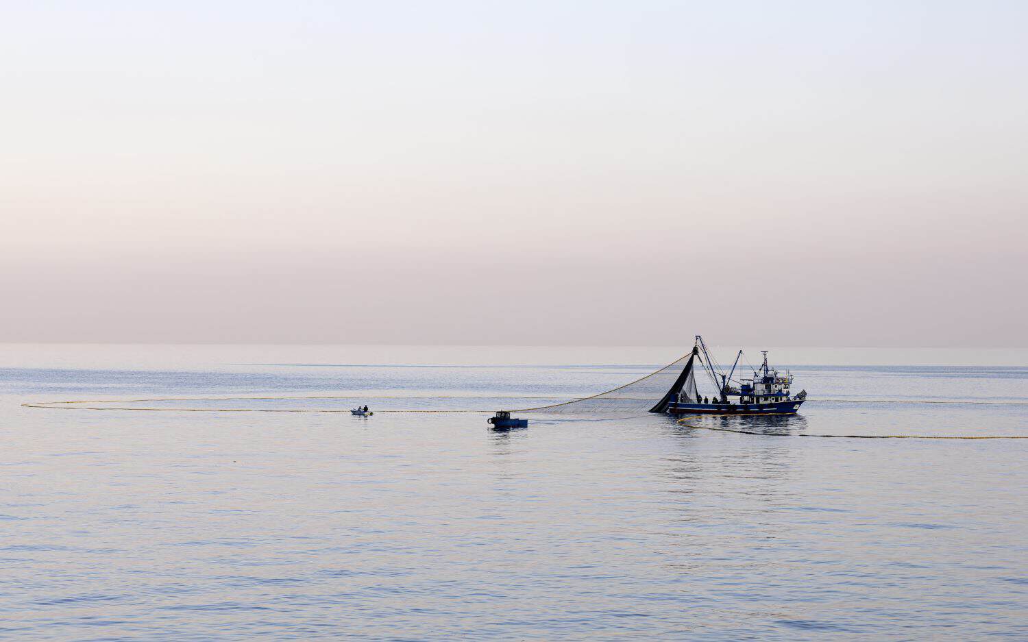The fishing boat is casting its nets into the sea hoping for a good catch.